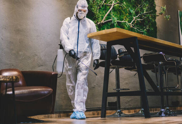 Man in protective suit spraying with disinfectant bar, cafe and restaurant interiors to prevent further spread of the coronavirus